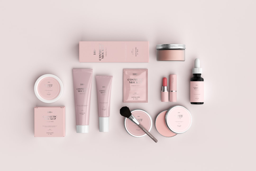 Assorted pink cosmetic containers, tubes, and a makeup brush on a pale background